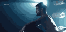 a man without a shirt sits in a dark room with the hashtag #rohpure on the bottom
