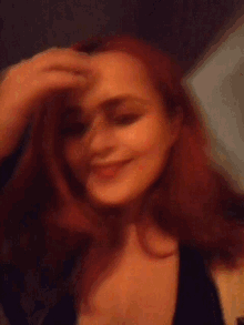 a woman with red hair is wearing a black top