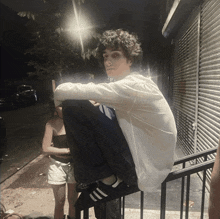 a young man squatting on a railing with a woman standing behind him