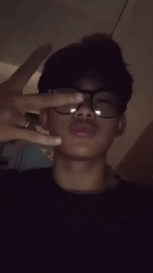 a man wearing glasses is making a peace sign