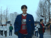 a man in a blue jacket and a red shirt with the number 10 on it is walking down a street .