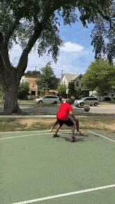 a man in a red shirt is playing basketball on a green court