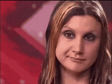 a close up of a woman 's face with a red background behind her