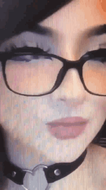 a close up of a woman 's face wearing glasses and a choker .