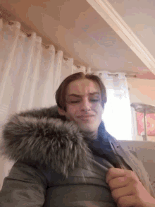 a woman wearing a fur hooded jacket looks down