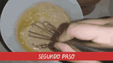 a person is whisking eggs in a bowl with the words segundo paso below