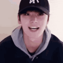 a young man wearing a hat and a hoodie is smiling .
