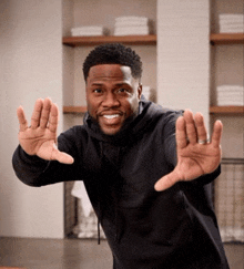 a man wearing a black hoodie is making a funny face with his hands outstretched