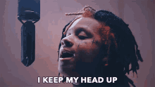 a man singing into a microphone with the words " i keep my head up " above him
