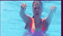 a woman in a red bikini is swimming in a pool with her hands in the air .