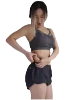 a woman in a gray top and black shorts is holding her stomach