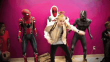 a group of people in superhero costumes are dancing in front of a pink wall ..