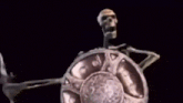 a skeleton is holding a sword and shield in a black background .