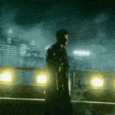 a man holding a gun stands in front of a city at night