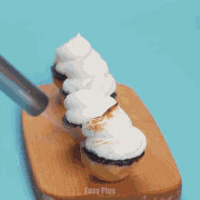 a wooden cutting board with cupcakes and easy plus written on it