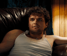 a man in a tank top is laying on a couch