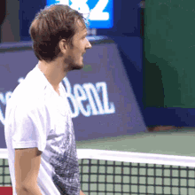 a man is standing on a tennis court in front of a sign that says benz