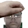 a hand is holding a man 's head with glasses on it .