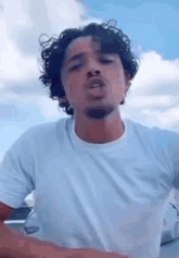 a man with curly hair and a beard is wearing a white shirt .