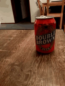a red can of double brown beer is on a wooden table