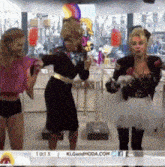 three women are dancing in front of a screen that says 10:13