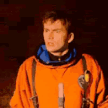 a man in an orange space suit with a microphone in his pocket
