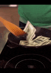 a person is cooking money in a pan with a wooden spatula