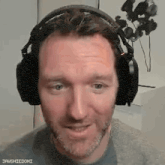 a man with a beard wearing headphones is smiling and looking at the camera .