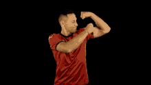 a man in a red shirt is flexing his muscles on a black background