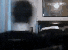 a dark room with a picture on the wall and a couch in the foreground