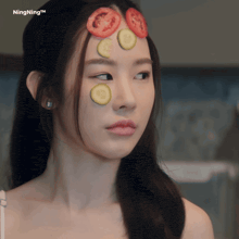 a woman with slices of tomatoes and cucumbers on her face has ningning written on the bottom
