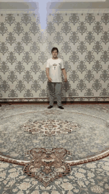 a man is standing on a rug in front of a wall with a pattern