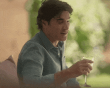 a man in a blue shirt is holding a glass of wine and a spoon