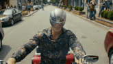 a man wearing a mask is riding a motorcycle down the street