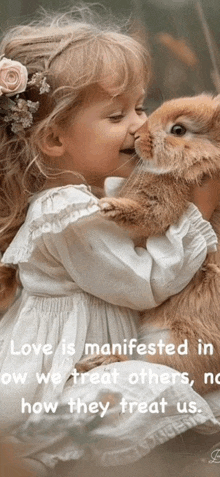 a little girl in a white dress is holding a small brown rabbit