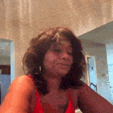 a woman in a red tank top is making a funny face while sitting at a table .