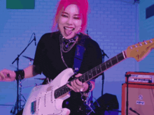 a woman with red hair is playing a white guitar in front of an orange amplifier