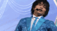 a man in a blue jacket and tie is singing into a microphone