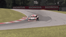a race car is going down a track with a honda banner behind it