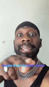 a man wearing a black tank top and a chain around his neck is pointing