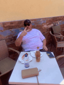 a man sitting at a table with a plate of food and a bottle of water