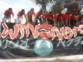 a group of people are standing on top of a sign that says ' winners ' on it