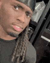 a man with dreadlocks is wearing a black headband and a black shirt .