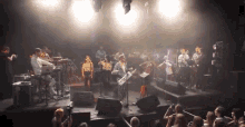 a group of people are playing instruments on a stage and one of them is holding a keyboard