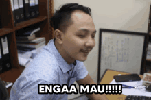 a man sitting at a desk with the words engaa mau !!! written on his face