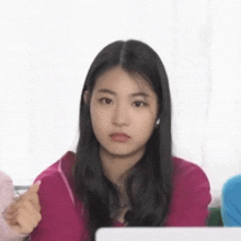 a young girl is sitting in front of a laptop computer and making a face .