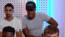 a man wearing a hat that says king is sitting next to two other men