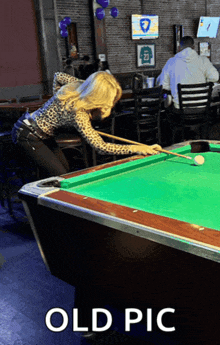 a woman is playing pool in a bar with the words old pic below her