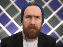 a man with a beard wearing a blue hat and headphones .