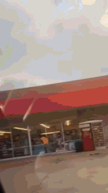 a gas station with a red awning and a red vending machine in front of it